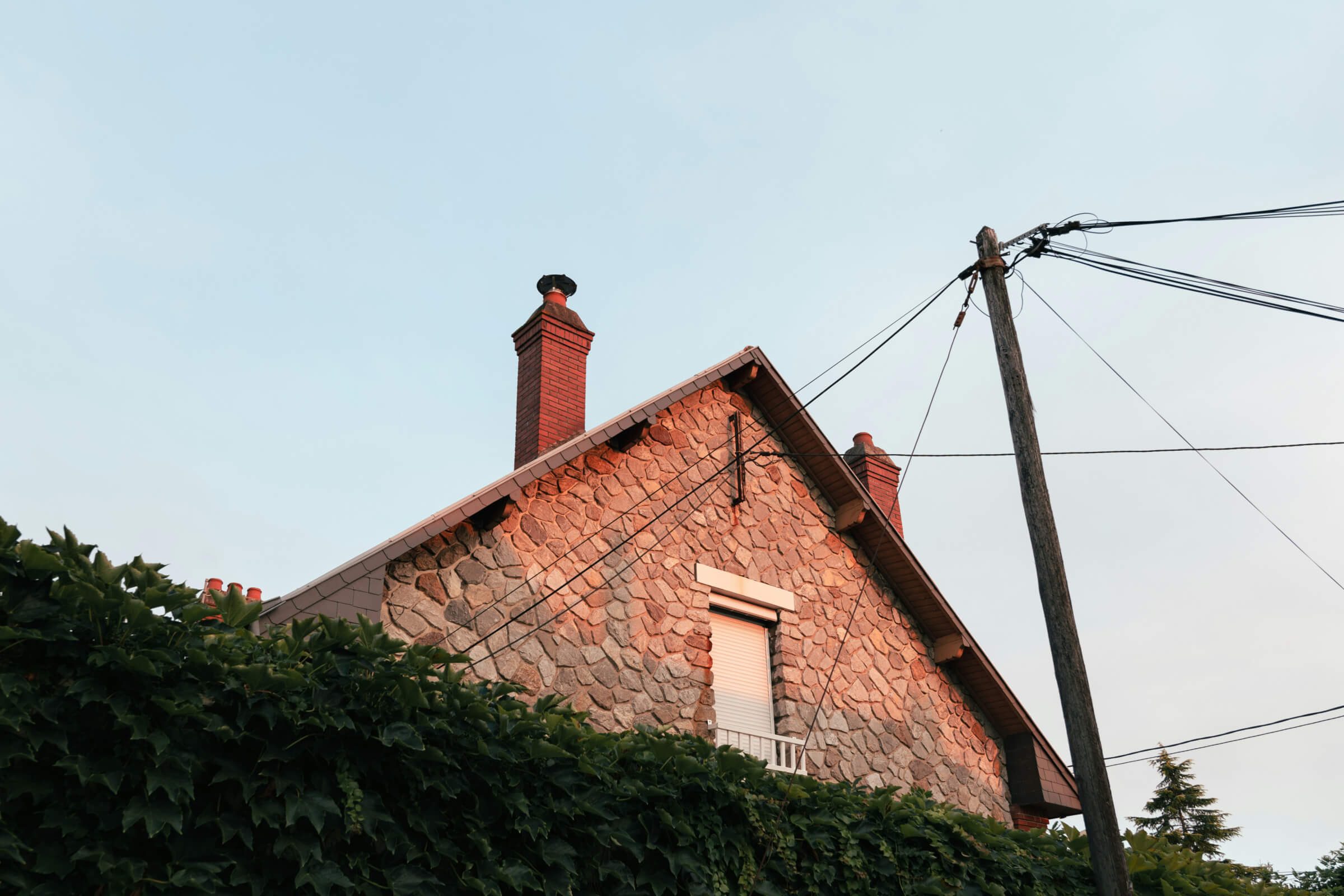 A brick roofline and chimney above a hedge